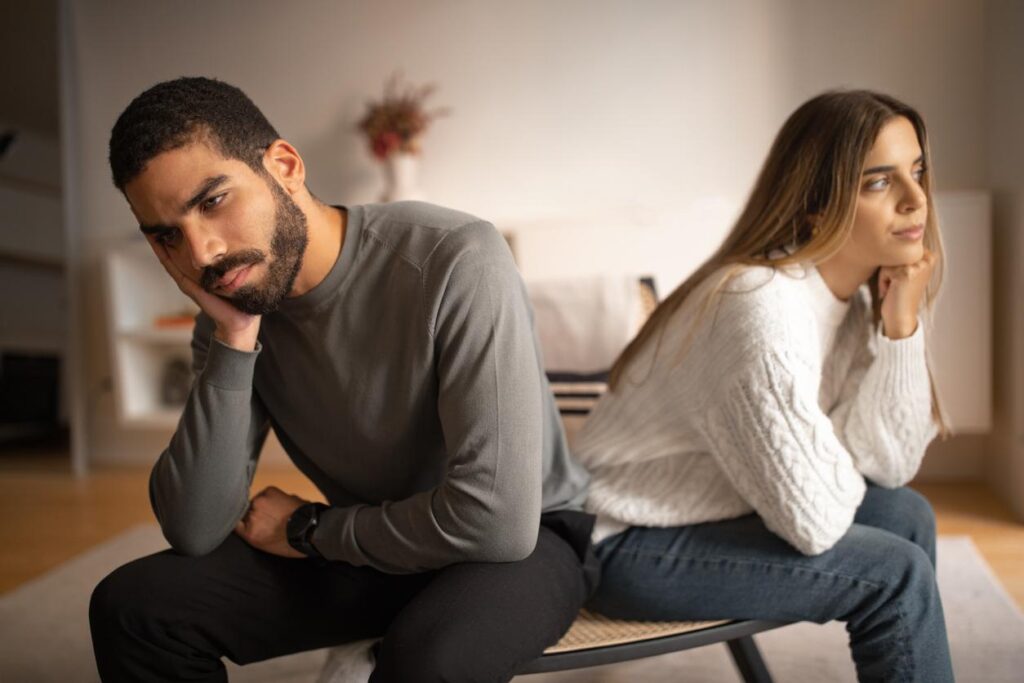 Young unhappy couple face away from each other in frustration