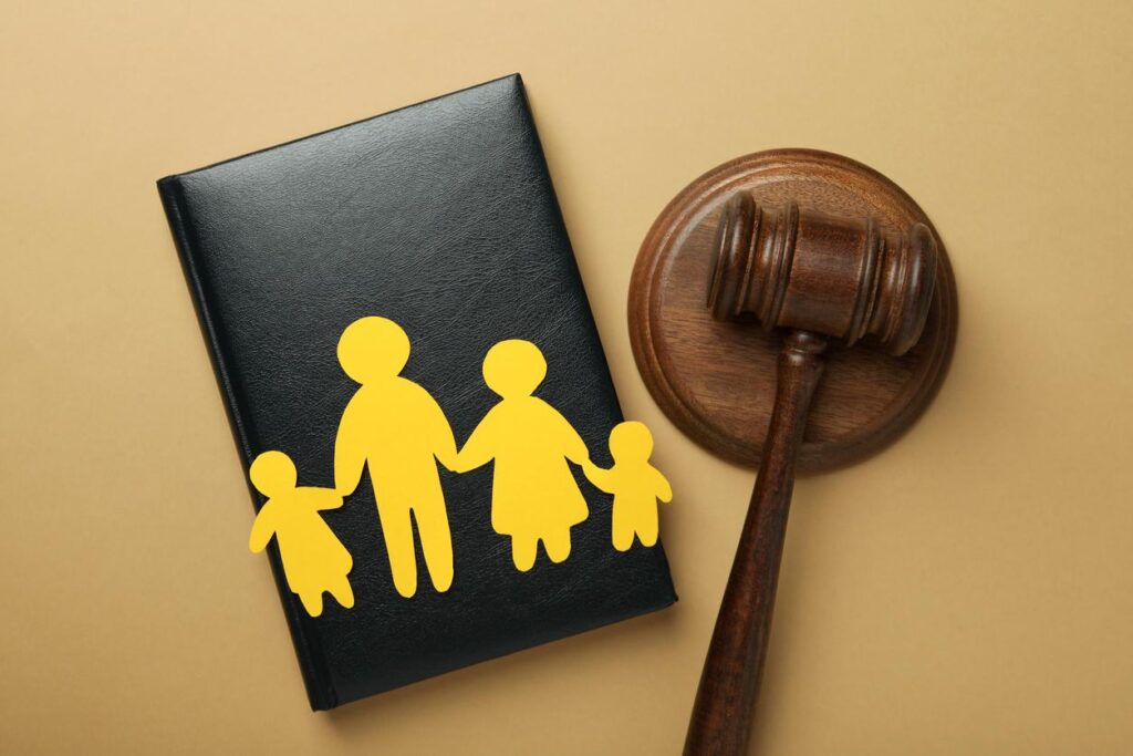 Paper cutout of family next to judge's gavel on tan background